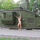Naked girl posing next to a tank in the town square