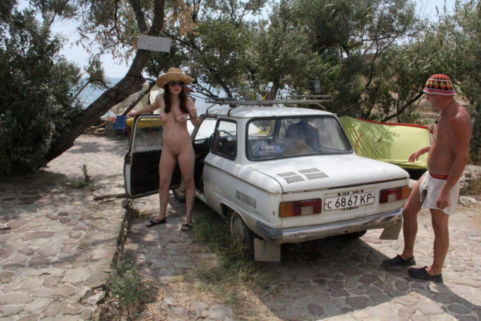 Naked redhead teen posing with a stranger and an old car
