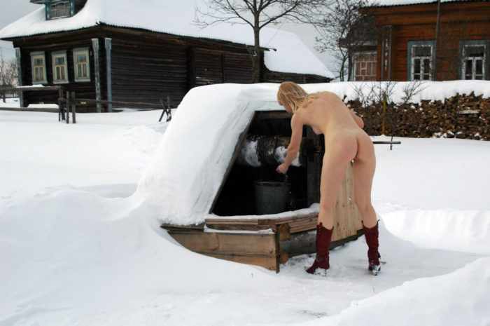 Smiling blonde pulls water from the well