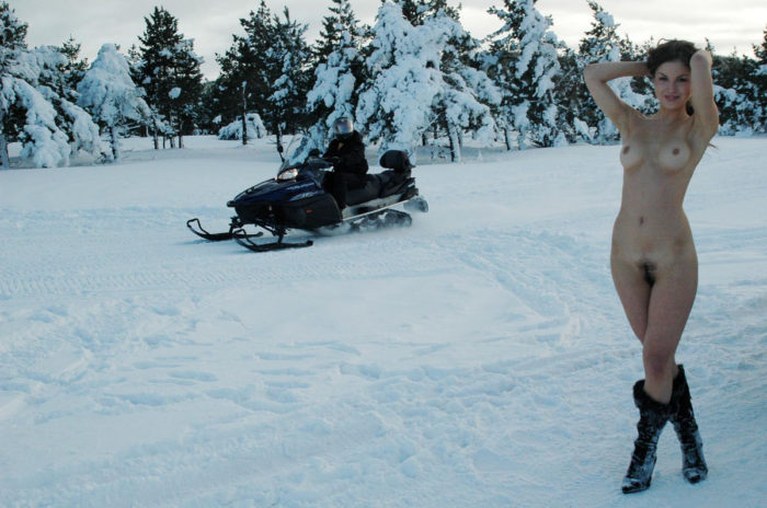 A girl without clothes posing on a snowmobile