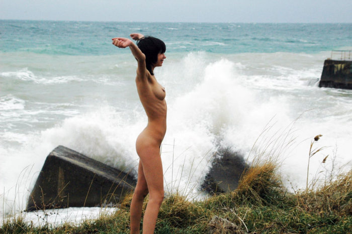 Girl posing next to the stormy sea