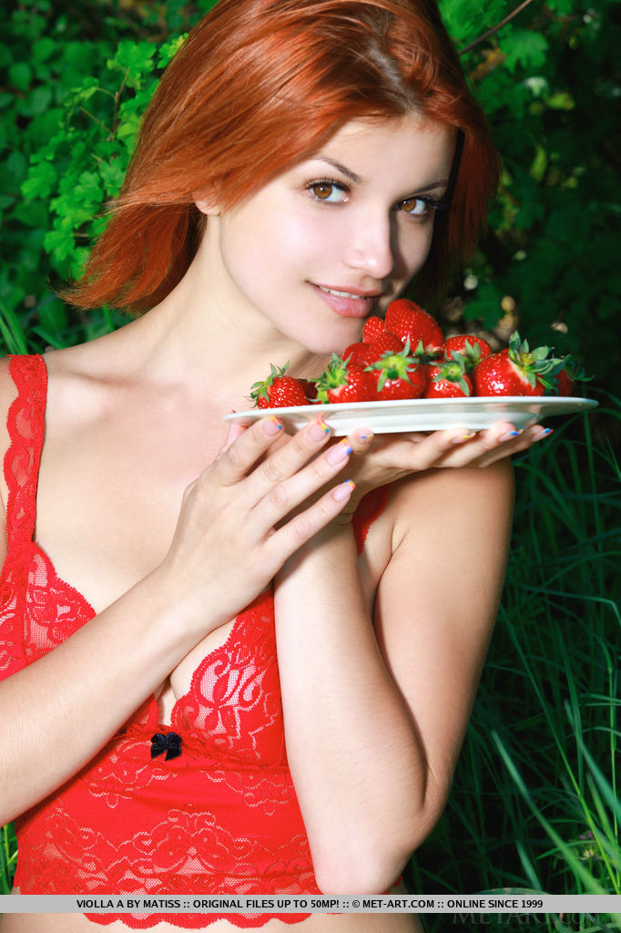 Naughty redhead Violla A posing in her bright red lace lingerie and a plateful of red strawberries, her porcelain skin and wonderful assets stands out in her lush surroundings.