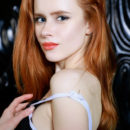 Redhead Bella Milano flaunts her petite, creamy body and pink cherry on the chair.