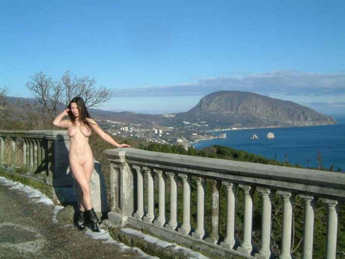 Young busty brunette posing at beautiful viewpoint