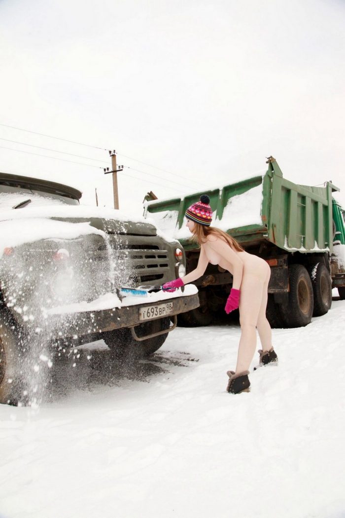 Blonde girl cleans snow from the truck
