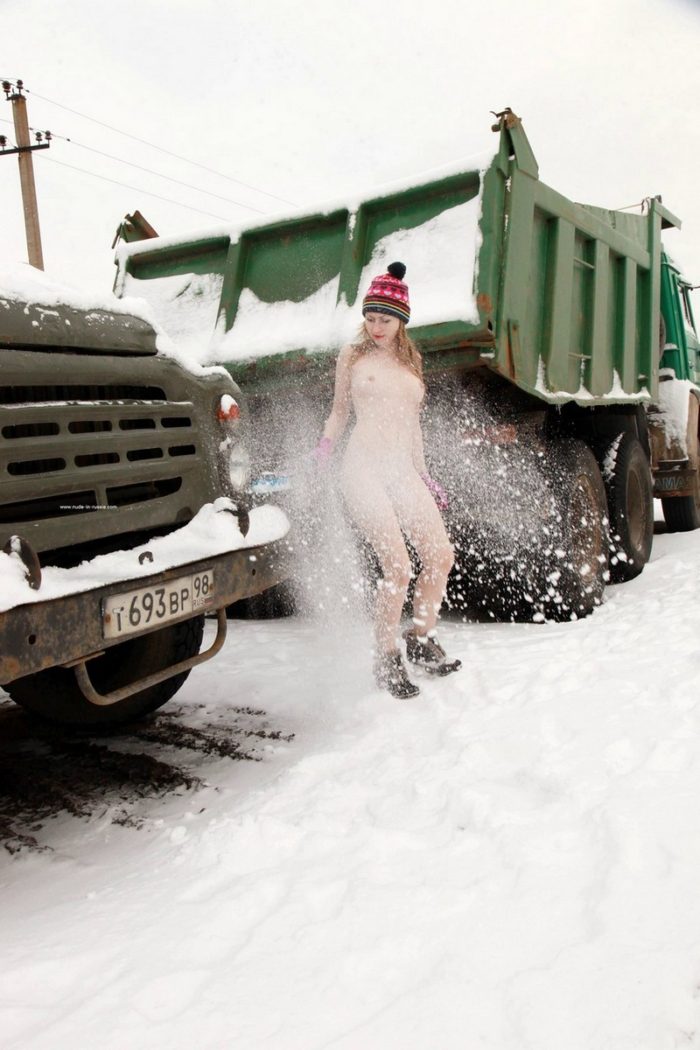 Blonde girl cleans snow from the truck
