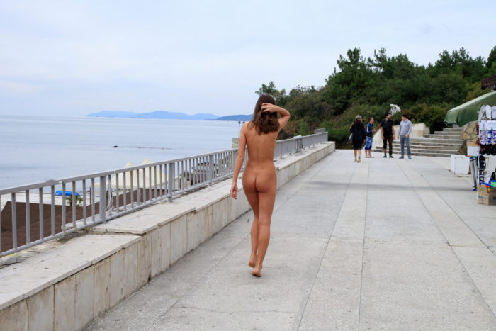 Pretty girl walks naked in the morning along the city embankment