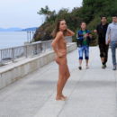 Pretty girl walks naked in the morning along the city embankment