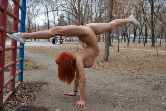 Red-haired girl doing gym exercises on the playground