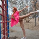 Red-haired girl doing gym exercises on the playground