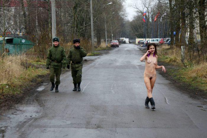 Slim girl posing in front of soldiers outdoors