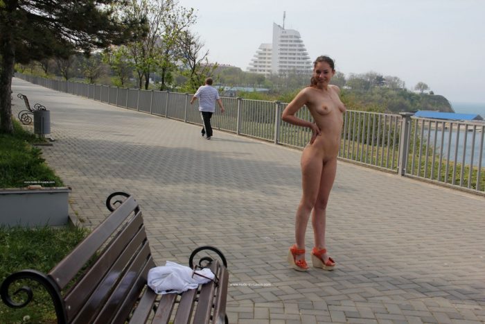 Smiling russian girl walks naked at public park