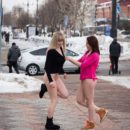 Two crazy babes play with snow at city center