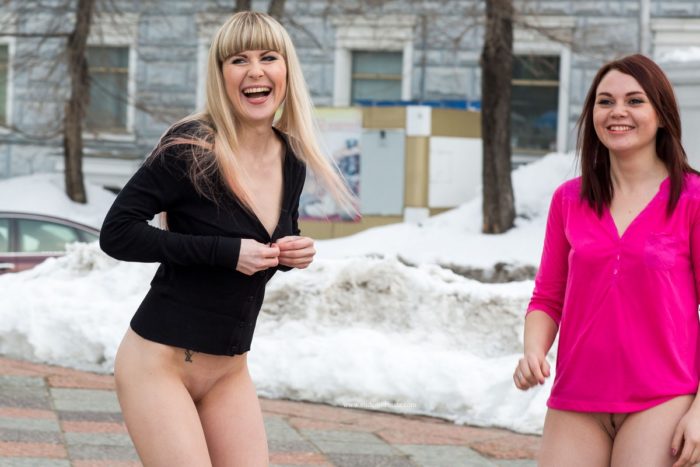 Two crazy babes play with snow at city center