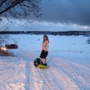Nude girl riding on snow saucer