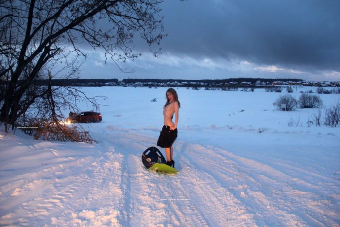 Nude girl riding on snow saucer