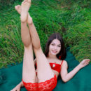 Delphina delightfully poses on the grass as she strips her red bikini baring her shaved pussy.