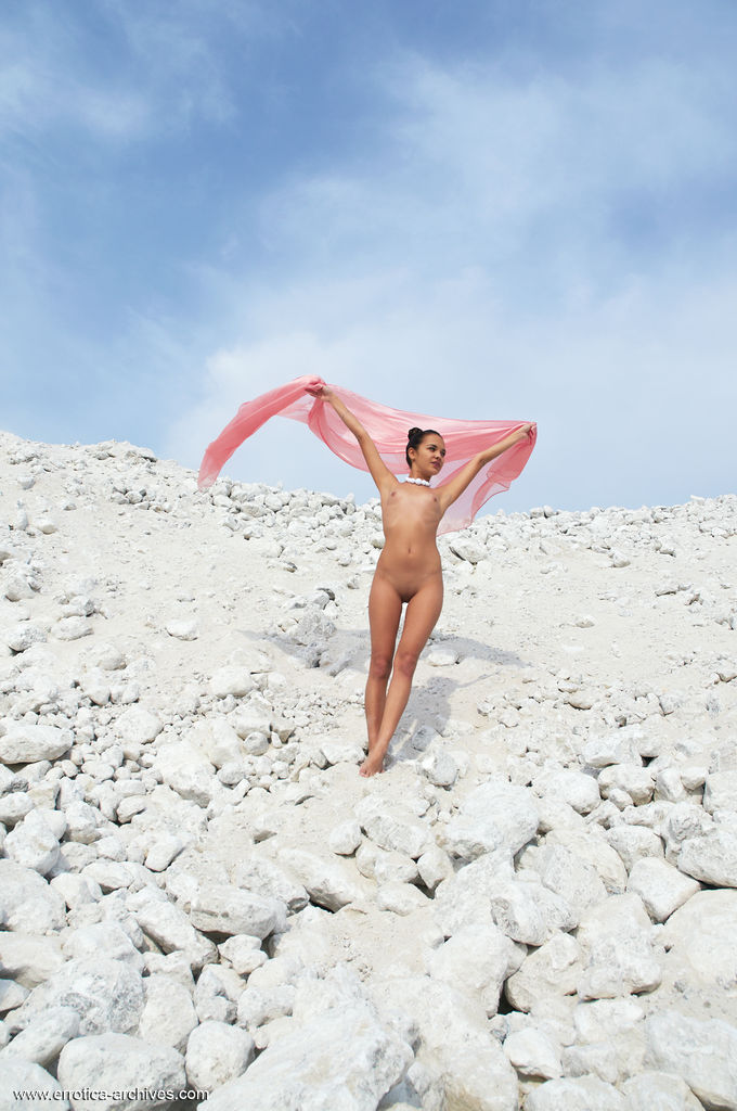 Romy flaunts her exotic olive-complexion body and pretty pink slit while posing a-top of white rock and ruble.