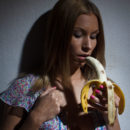 Daisy A sucks a mouthful of ripe banana while stroking her sensitive pink clit.