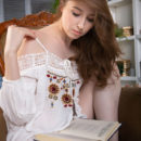 Ginger Frost reads her favorite book as she undress her white tassled dress on the chair.
