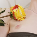 Jia is naked on the couch. She plays with a yellow rose, sliding it all over her smooth body.