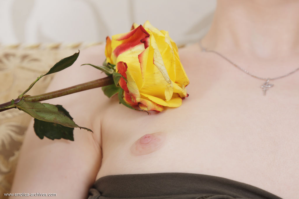 Jia is naked on the couch. She plays with a yellow rose, sliding it all over her smooth body.