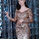 Long-haired brunette Velana sparkles in a short dress goes nude on the couch showing her shaved pussy.