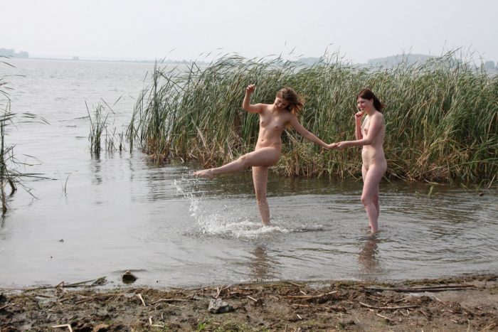 Two girls posing naked outdoors near car