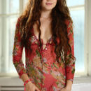 Wearing a lovely colorful top with long brown wavy hair Norma A commands your attention