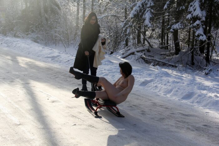 Naked brunette riding a snow scooter