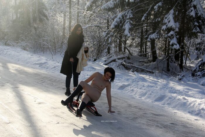 Naked brunette riding a snow scooter