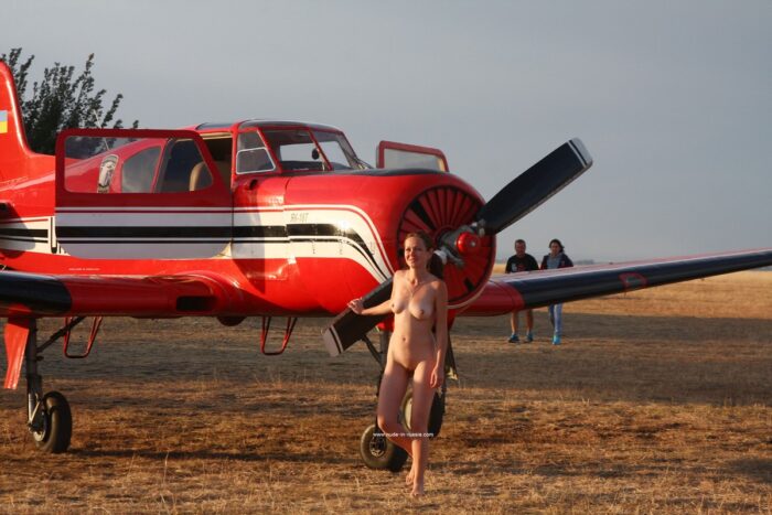 Naked girl Asja K next to a small plane