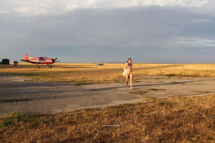 Naked girl Asja K next to a small plane