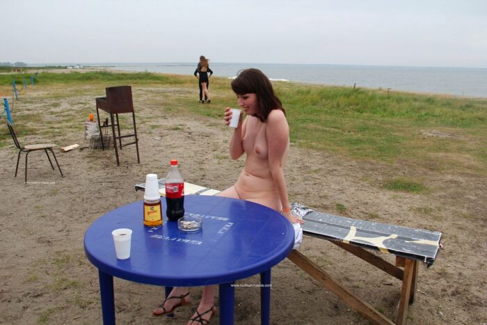 Naked girl drinks whiskey cola on the lake