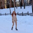 Red-haired girl skating on a winter street