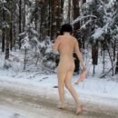 Brunette Klara in bright socks at snowy road in the forest