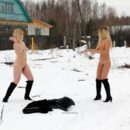 Two blondes throw snowballs at each other on a village road