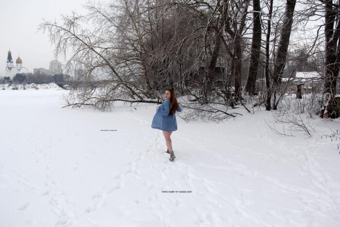 Young busty girl Dana playing with snow on a frozen lake