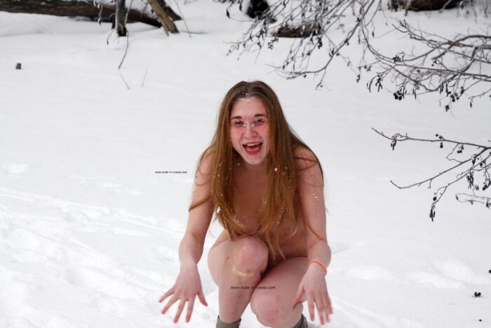 Young busty girl Dana playing with snow on a frozen lake