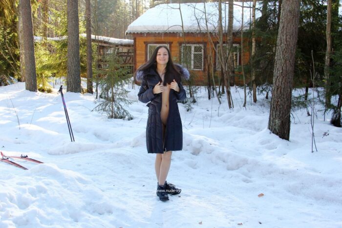 Smiling girl Lera without clothes is skiing in the forest