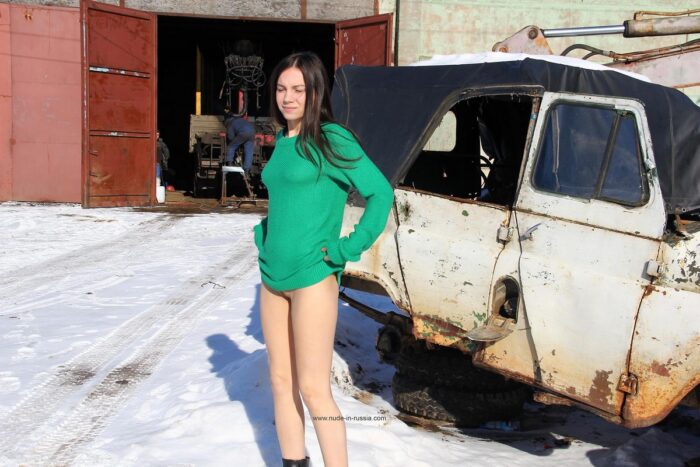 Young brunette Lera in black boots by the old car