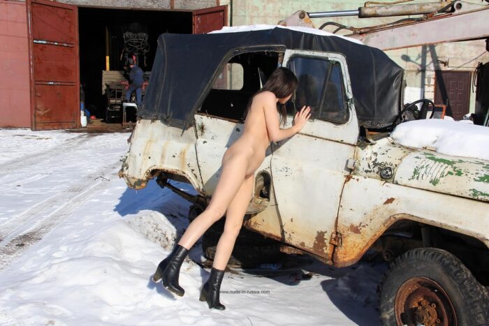 Young brunette Lera in black boots by the old car
