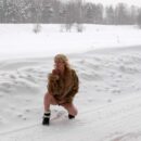 Blonde Diana takes off her fur coat on a snowy road