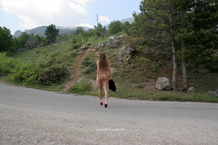 Young girl Masha E with pink handbag on a mountain road