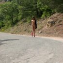 Young girl Masha E with pink handbag on a mountain road