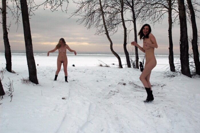 Blonde and brunette playing snowballs without clothes at winter