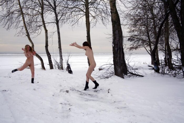 Blonde and brunette playing snowballs without clothes at winter