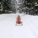 Smiling blonde Diana plays with a snow at winter road