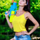 Martina Mink is ready to shoot a watergun and play by the river bank. She decides to take off her yellow tank top and shorts and uncover her juicy melons and hairless pussy.