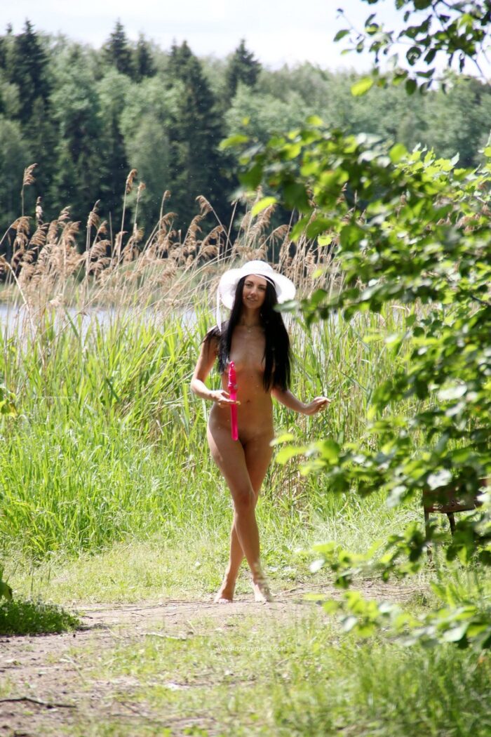 Russian brunette Veronica Snezna in white hat plays with soap bubbles in the forest
